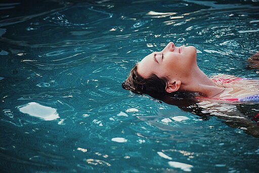 Eine Frau im Wasser, auf dem Rücken schwimmend