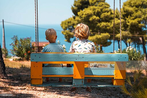 Zwei Kinder sitzen auf einer Bank.