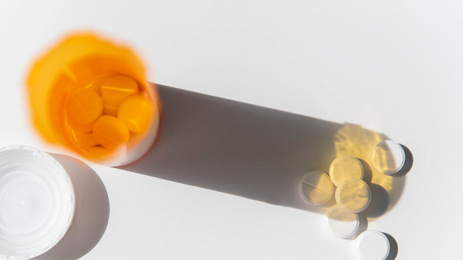 Tabletten auf einem Tisch neben einer Medikamentendose