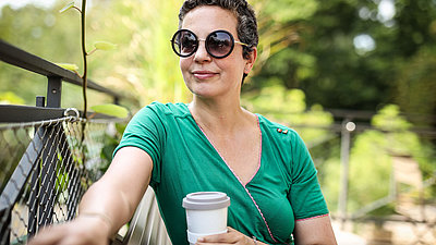 Alexandra von Korff mit Sonnenbrille und Coffee-to-go-Becher blickt gelassen in die Ferne
