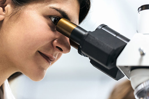 Eine Frau blickt in ein Mikroskop.