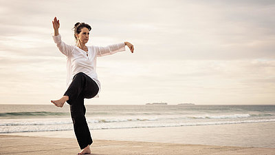 Eine Frau macht Tai-Chi-Übungen am Strand