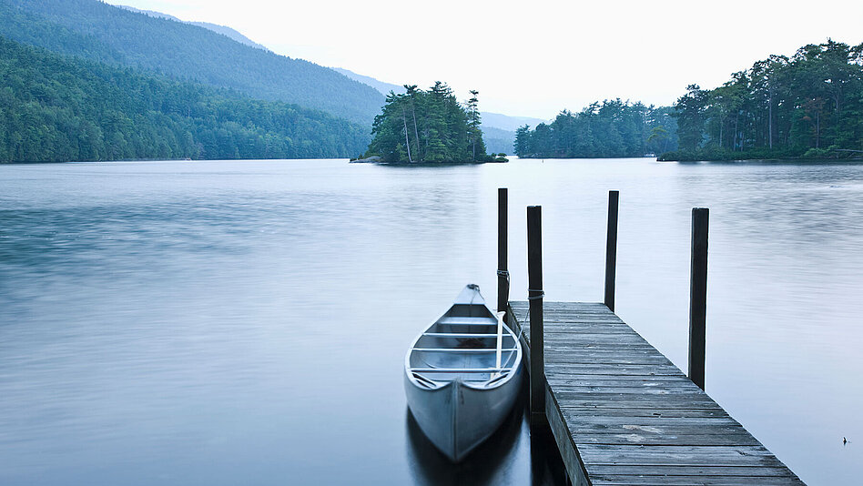 Ruderboot an Steg festgebunden auf ruhigem Gewässer