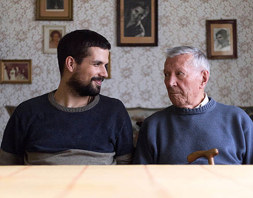 Ein junger und ein alter Mann sitzen nebeneinander und blicken sich gegenseitig an