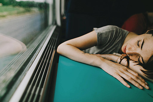 Schlafende Frau mit dem Kopf auf einem Tisch im Zug