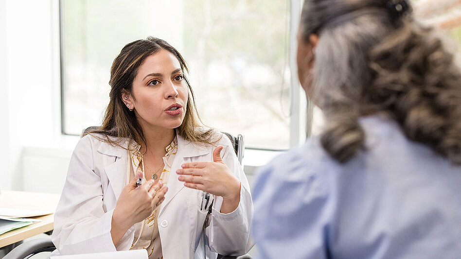 Mittelerwachsene Ärztin gestikuliert, während sie dem Patienten ihre Empfehlung erklärt