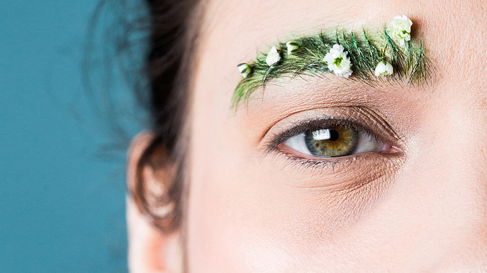Nahaufnahme vom Gesicht einer Frau mit Augenbraue aus denen Blüten sprießen