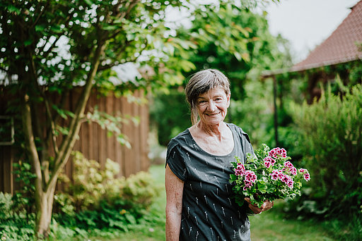 Maria Menzlaw mit Blumenstrauß in ihrem Garten