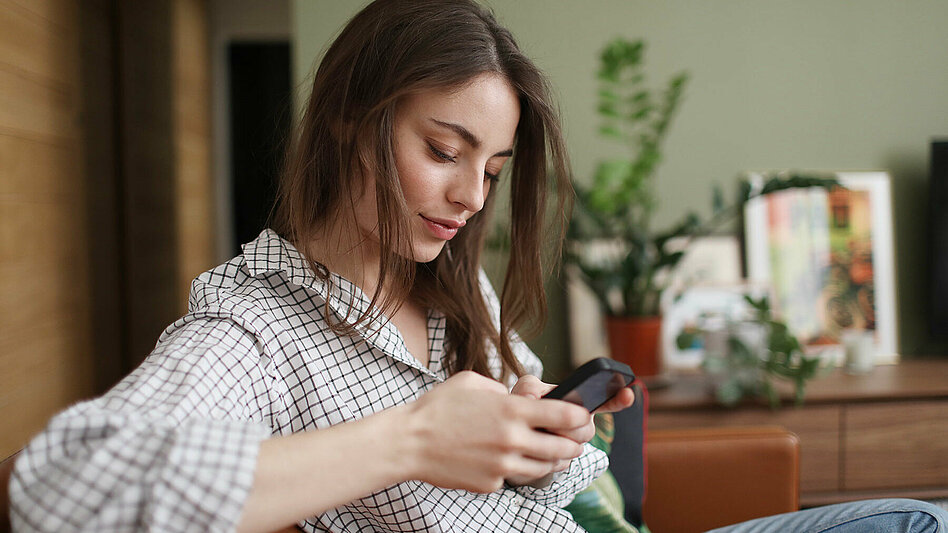 Eine junge Frau blickt auf ihr Smartphone