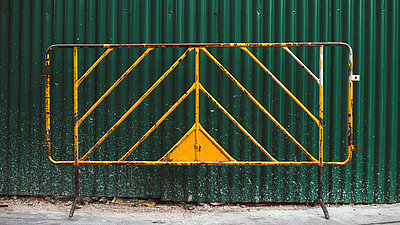 Ein Element eines gelben Schutzzauns vor einem grünen Container