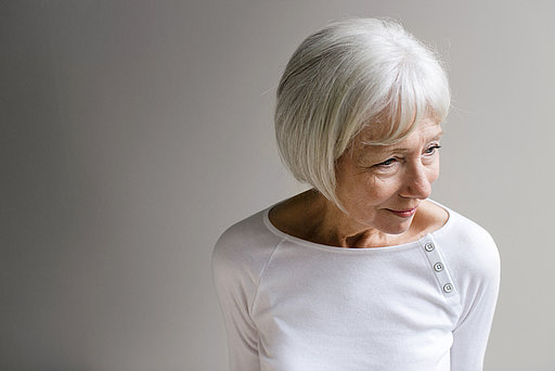 Ältere Frau mit weißen Haaren in weißem Pullover.