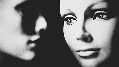 Schwarz-weiß-Aufnahme: Im Vordergrund ein weibliches, im Hintergrund ein männliches Gesicht.
