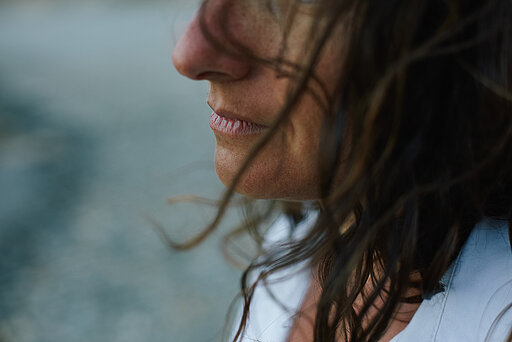Ausschnitt aus Portraitbild einer Frau im Profil, deren Haare im Wind wehen 