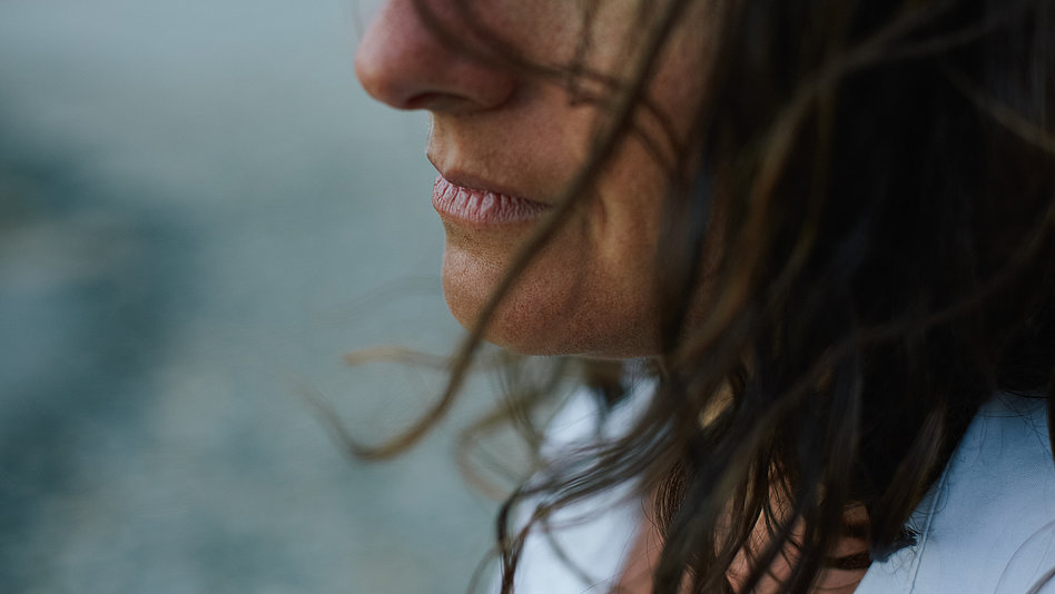 Ausschnitt aus Portraitbild einer Frau im Profil, deren Haare im Wind wehen