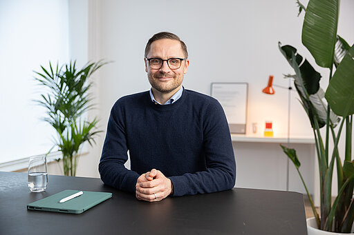 Bild von Onkologe Dr. Benedikt Westphalen, der an einem Schreibtisch sitzt