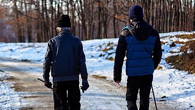 Zwei Personen wandern durch eine schneebedeckte Waldlandschaft