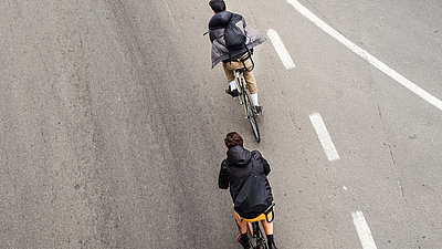 Zwei Radfahrer auf einer asphaltierten Straße.