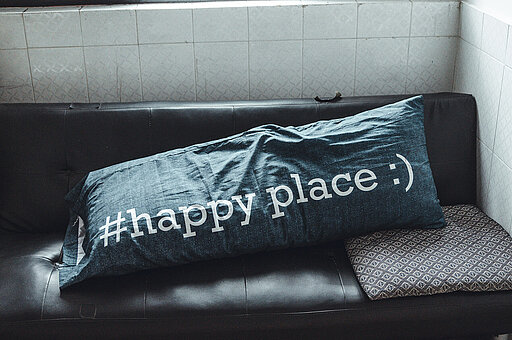 Sofa mit überdimensional großem Kissen mit der Aufschrift #happyplace und Smiley