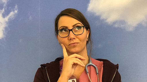 Onkologische Fachpflegerin Anna in Arbeitskleidung und nachdenklicher Pose