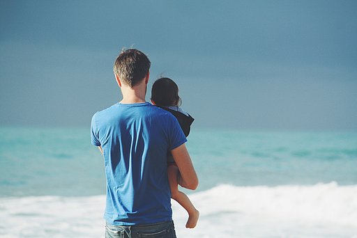 Erbliche Vorbelastung bei Darmkrebs: Mann und Kleinkind blicken aufs Meer 