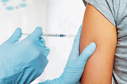 Impfspritze am Oberarm einer Patientin 