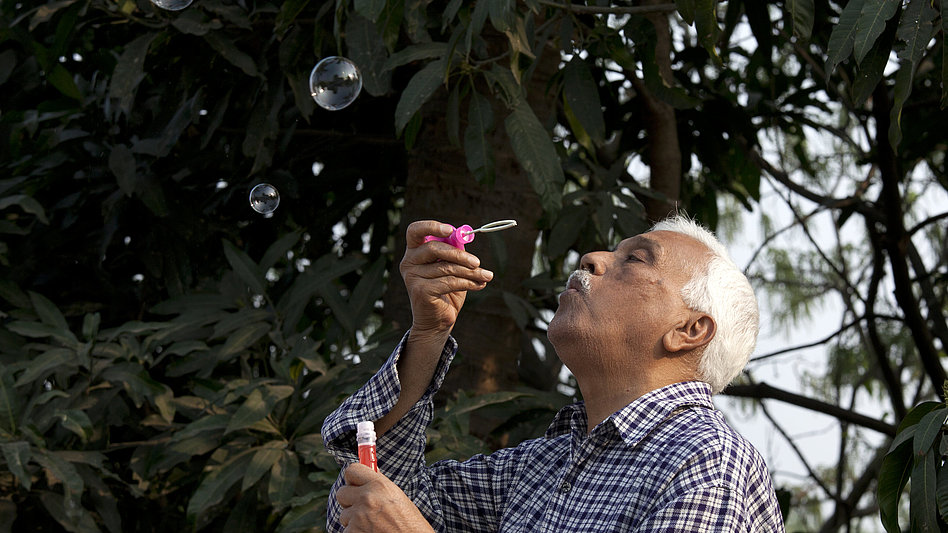 Ein älterer Mann pustet Seifenblasen in die Luft