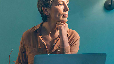 Eine Frau sitzt nachdenklich vor einem Laptop
