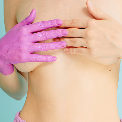 Eine Frau legt ihre Hände auf ihre Brust – eine der Hände ist in Pink eingefärbt