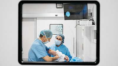 Chirurgin und Chirurg hinter einem Fenster im Operationssaal