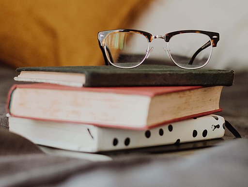 Eine Brille liegt auf einem Bücherstapel