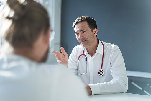 Arzt im Gespräch mit männlichem Patienten.