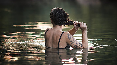 Eine Frau steht brusttief in einem See im Wald