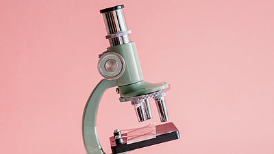 Weißes Mikroskop vor rosa Hintergrund