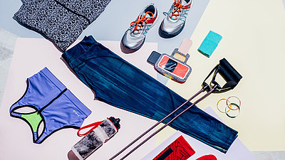 Sportschuhe, Trinkflasche und Sportkleidung liegen auf dem Boden