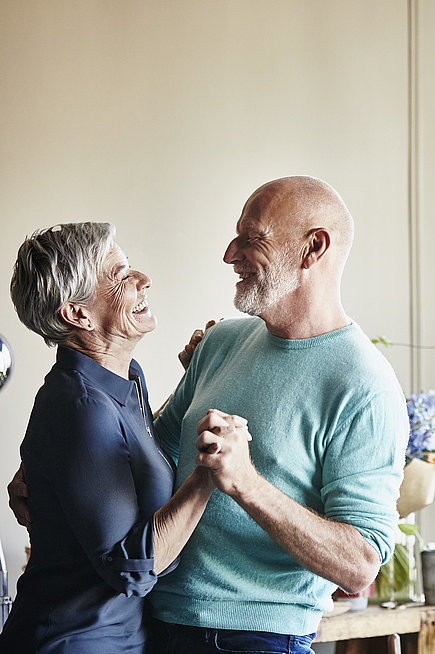 Älteres Paar tanzt gemeinsam in der Wohnung.