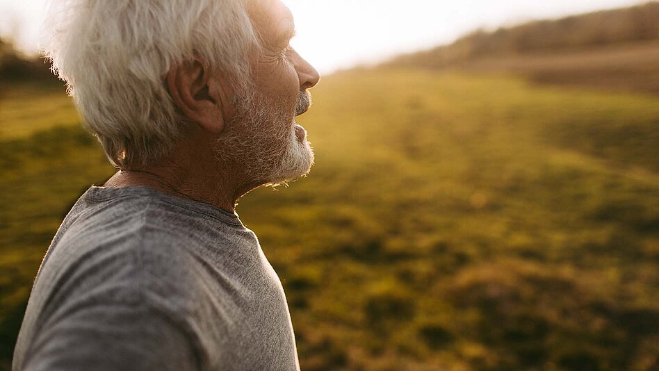 daskwort_nach der therapie beim dlbcl Älterer Mann genießt den Sonnenuntergang im Freien – entspanntes Porträt in warmem Abendlicht, Symbol für Achtsamkeit, Gesundheit und Lebensfreude.