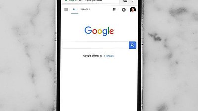 Ein Handy-Display zeigt die Startseite von Google.