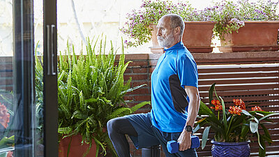 Älterer Mann trainiert Ausfallschritte zu Hause auf der Terrasse