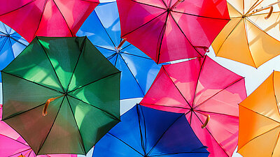 Viele aufgespannte bunte Regenschirme bilden ein schützendes Dach