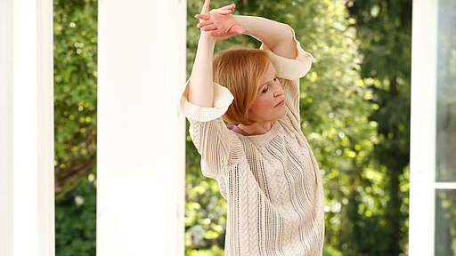 Yogalehrerin Stefanie zeigt eine Yogaübung zur Seitendehnung im Stehen 