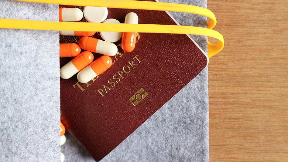 Tabletten und ein Reisepass ragen aus dem Gepäck hervor